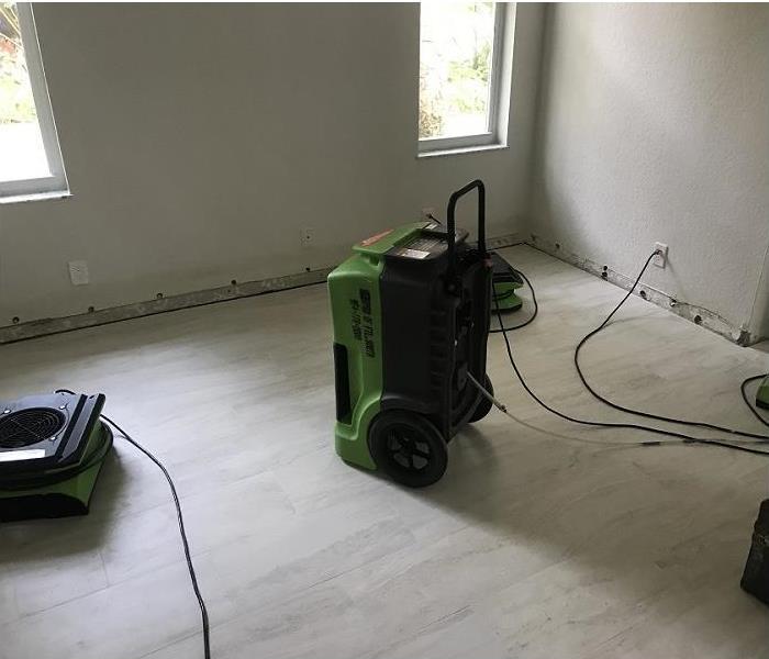 SERVPRO restoration eqiupmet in water daaged room; baseboards removed; water stains on wall