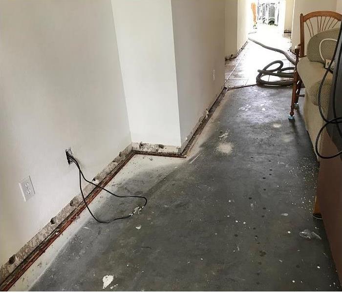 water damaged hallway of commercial property; flooring and baseboards removed for drying